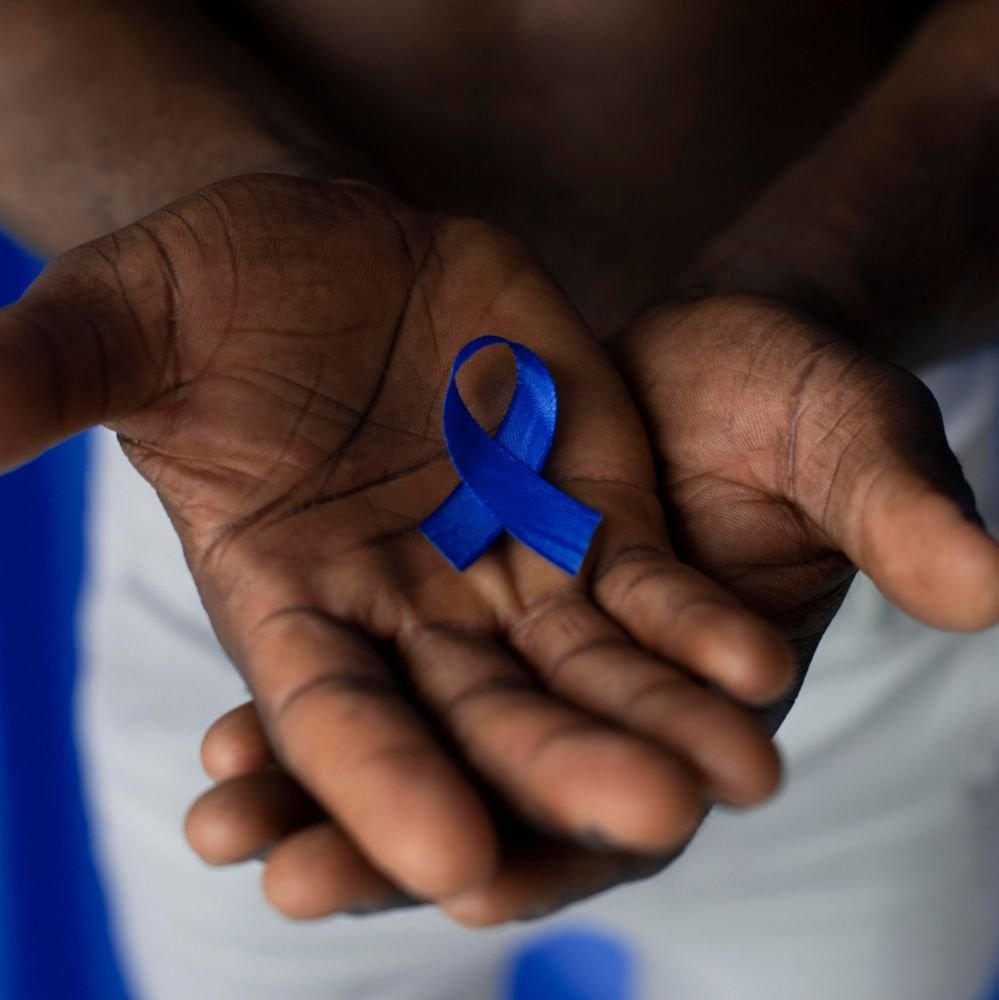 Homem segurando laço azul em homenagem ao Dia nacional de combate ao câncer